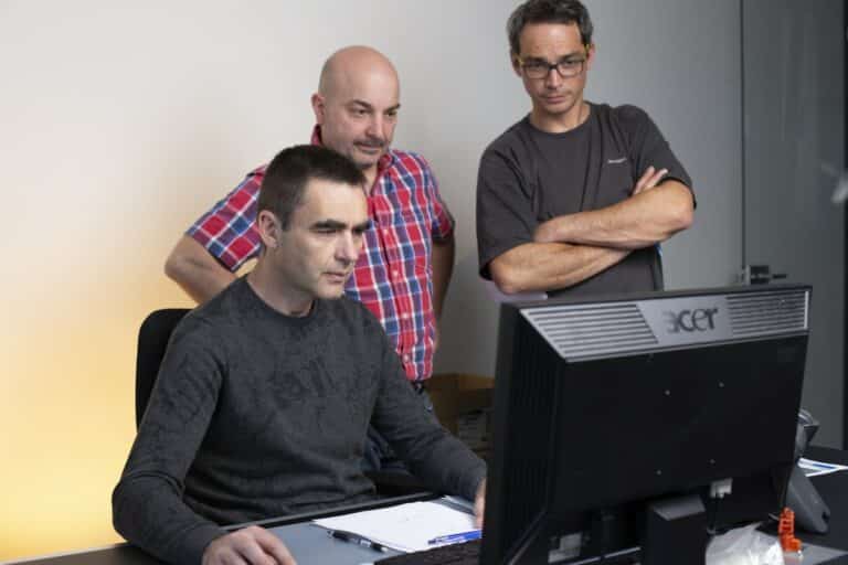 Trois techniciens examinant attentivement les données sur un écran d'ordinateur