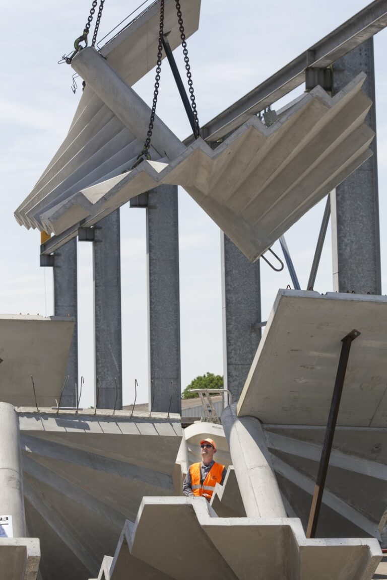 ouvrier maniant une grue avec des escaliers en béton accrochés