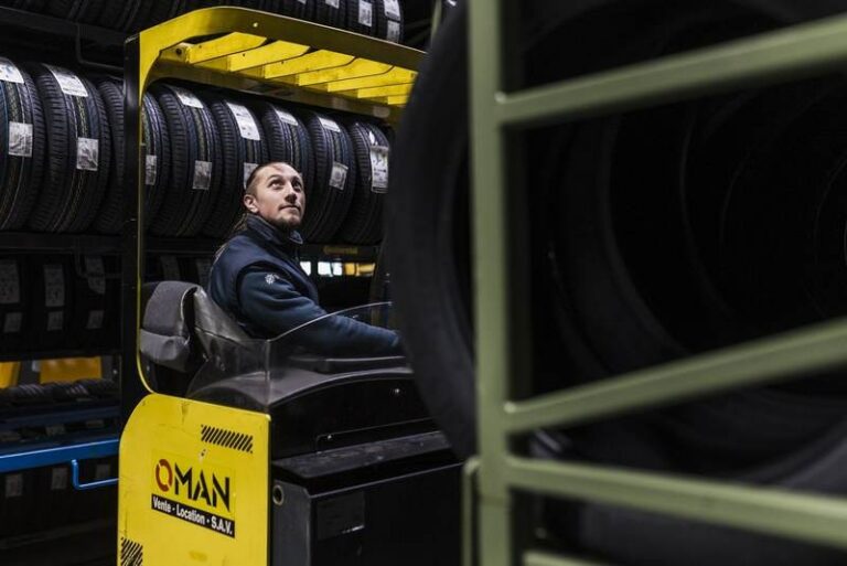 Opérateur attentif manoeuvrant un chariot élévateur dans un entrepôt de pneus, capturé par un photographe spécialisé dans l'industrie