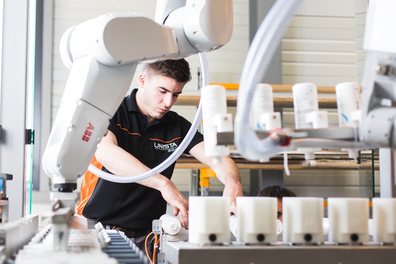 Un technicien qualifié travaille côte à côte avec un bras robotique automatisé dans une usine industrielle, une illustration de l'interaction humaine-machine capturée par un photographe industriel