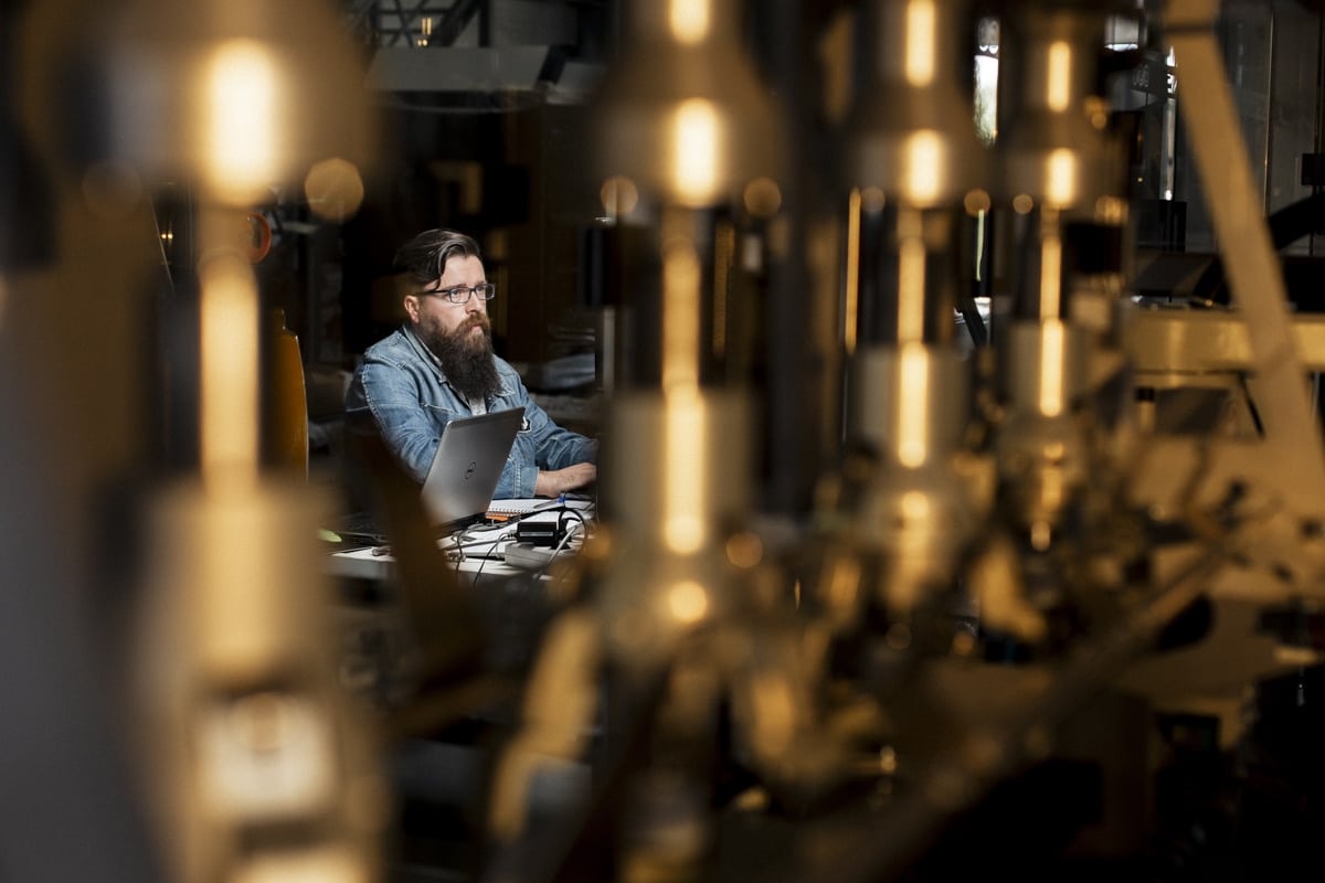 Ingénieur concentré sur son ordinateur dans un décor industriel, capturé par un photographe professionnel.