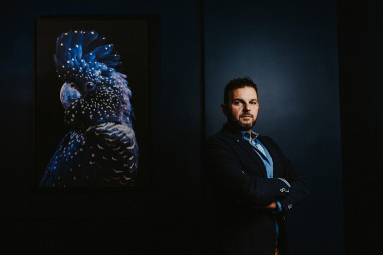 Portrait créatif d'un chef d'entreprise confiant, capturé par un photographe de portrait, avec un tableau artistique d'un perroquet en arrière-plan soulignant sa présence