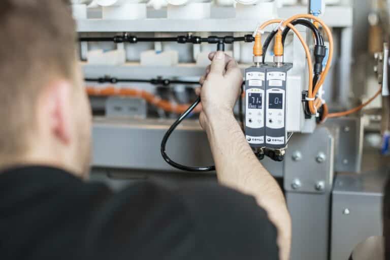 Technicien industriel réglant un équipement automatisé avec un instrument de mesure