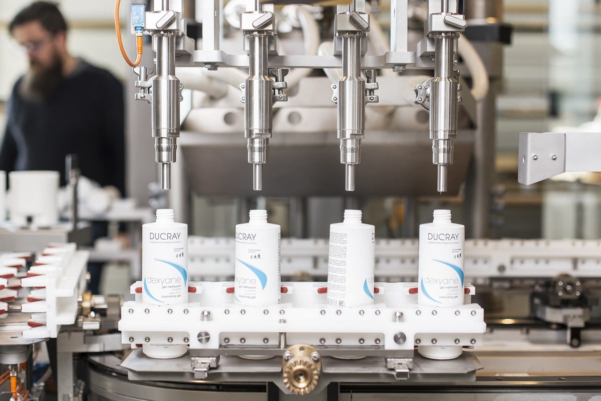 Équipement robotisé manipulant des produits cosmétiques dans une usine, illustré par un reportage photo professionnel