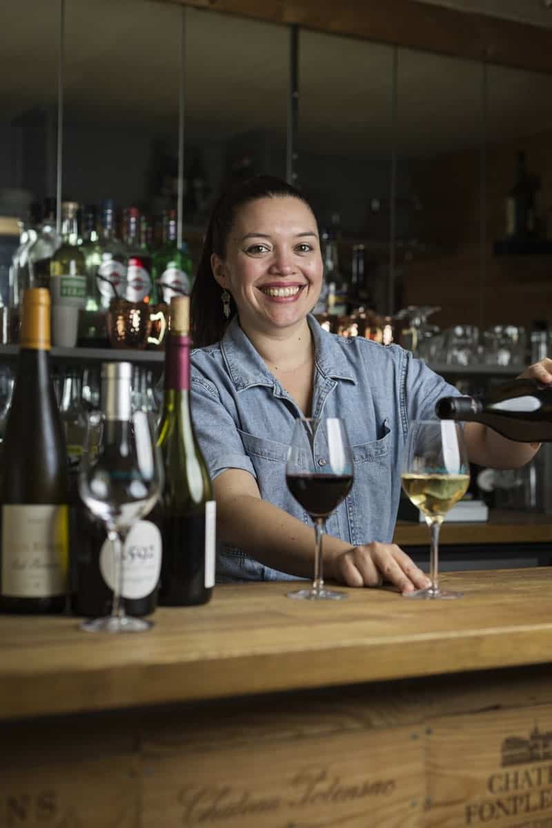 portrait d'une serveuse de restaurant servant un verre derrière le bar