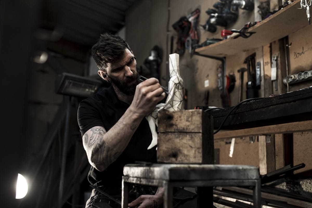 sculpteur dessinant sur sa maquette dans son atelier