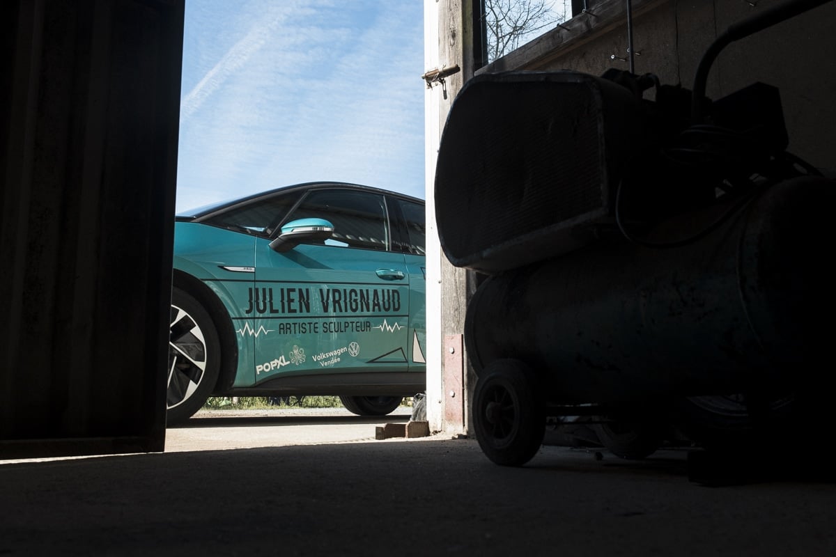 voiture électrique verte devant porte de hangar