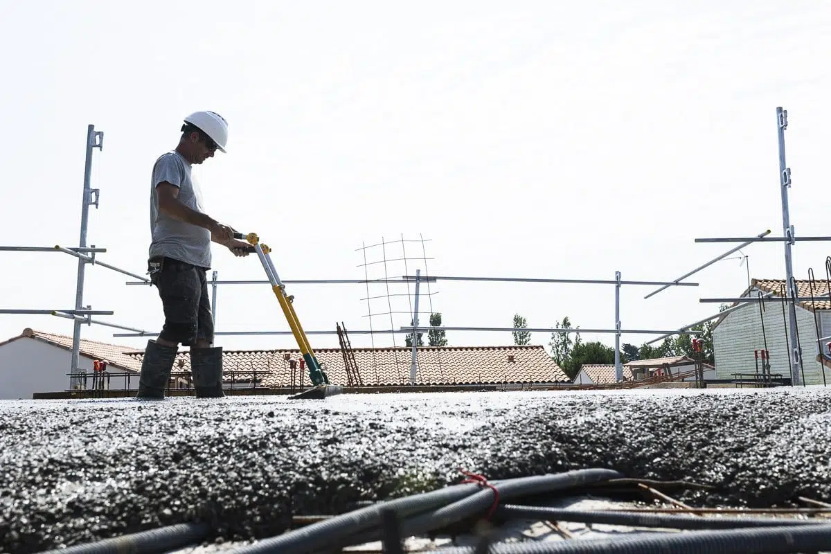 Ouvrier du BTP nivelant la surface fraîchement bétonnée sur un chantier de construction à La Barre-de-Monts