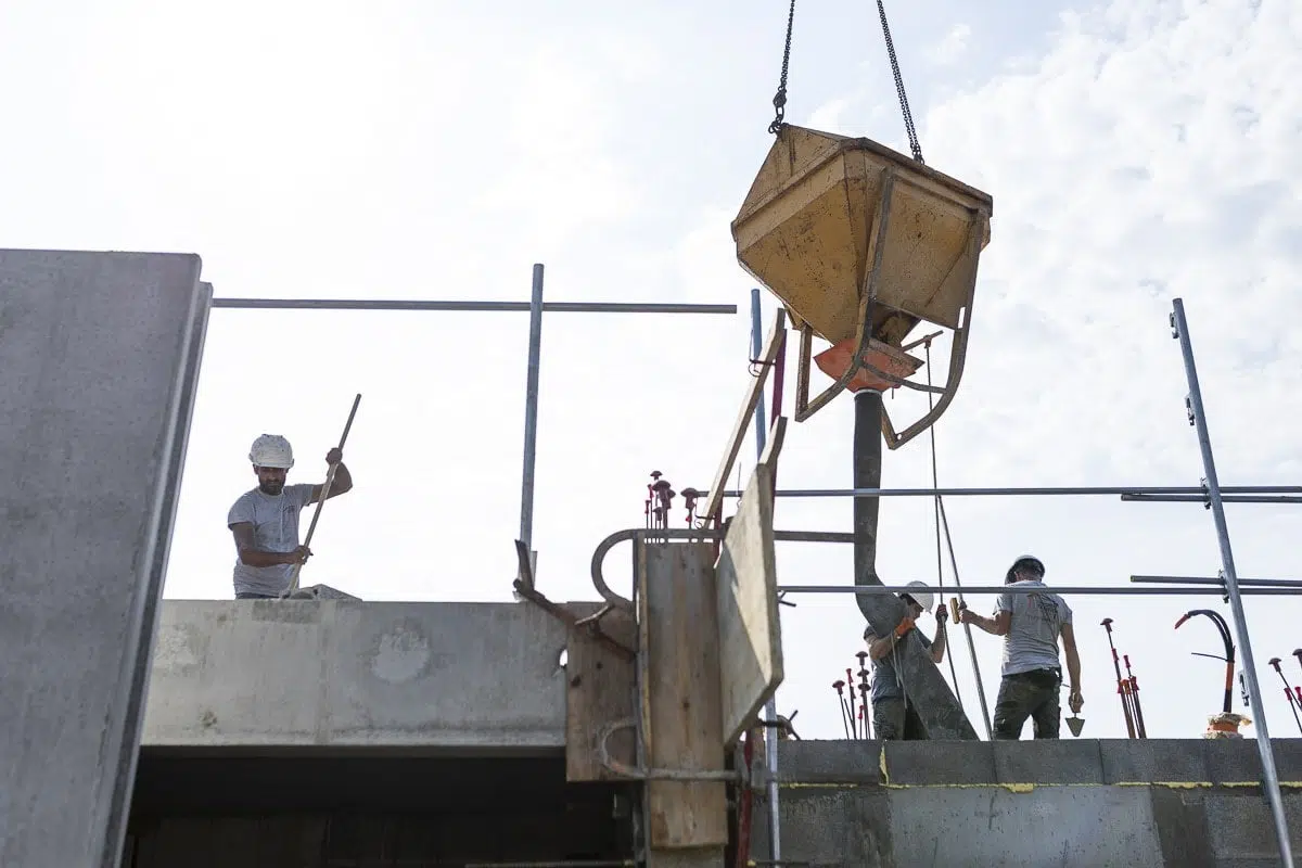 Équipe de maçons coulant le béton à l’aide d’une benne suspendue - Photographie de terrain en Vendée