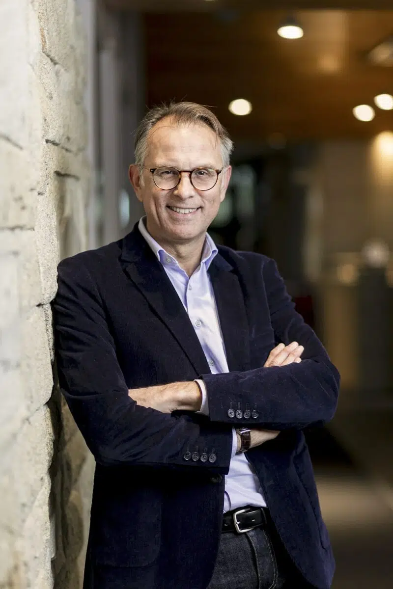 portrait professionel d'un homme en costume appuyé sur un mur en pierre
