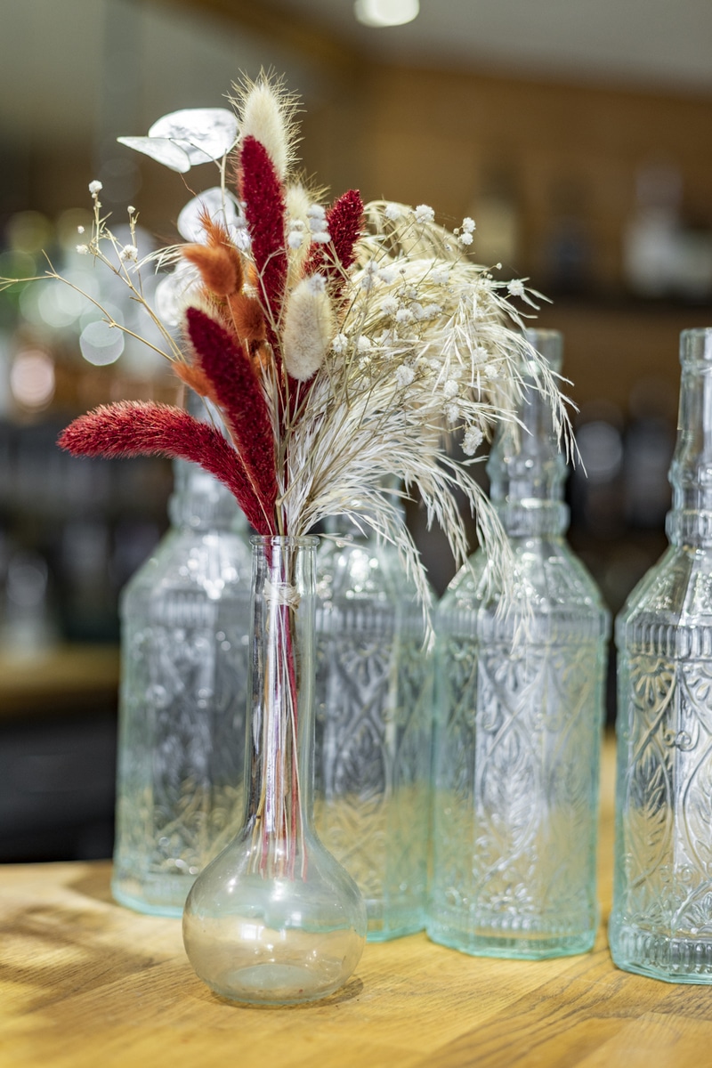Bouteille en verre, contenant des fleurs sur un bar